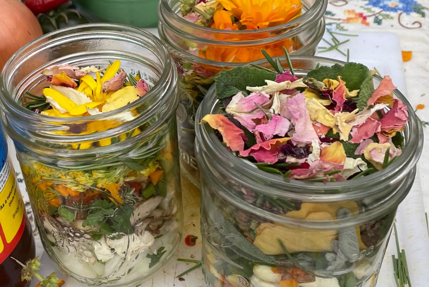 Jars of calendula, rose, and fresh-cut herbs ready for tincture